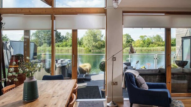 Un intérieur moderne avec de grandes fenêtres, une table à manger en bois et une vue sur un lac.