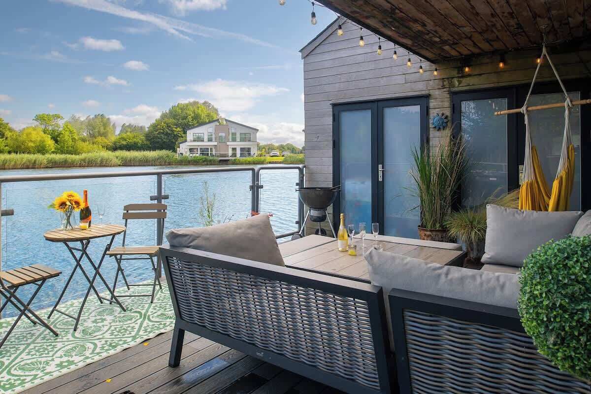 A deck with outdoor furniture, a grill, and a view of a body of water.