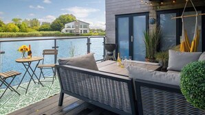 Une terrasse dotée de mobilier d’extérieur, d’un barbecue et offrant une vue sur un plan d’eau.
