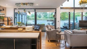 A modern kitchen with a built-in island, a seating area with sofas, and a large window offering a view of the outdoors.