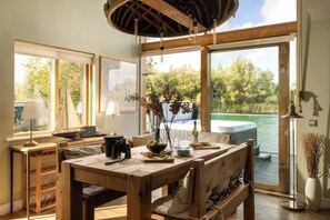 A wooden dining table with chairs, a laptop, and a vase with branches.