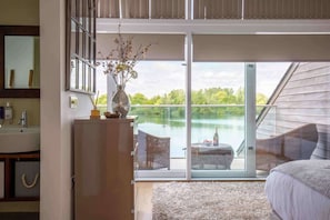 A bedroom with a large sliding glass door leading to a balcony overlooking a lake.