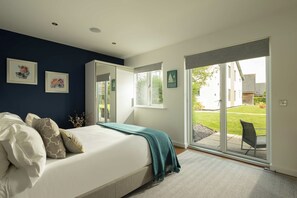 A bedroom with a bed, a large window, and a view of the outdoors. - Malachite Lodge (South Cerney)