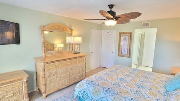 Un dormitorio con cama, cómoda y ventilador de techo.
