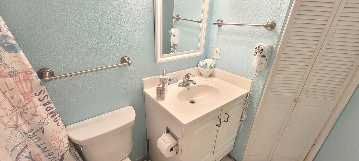 A bathroom with a toilet, sink, and towel rack.