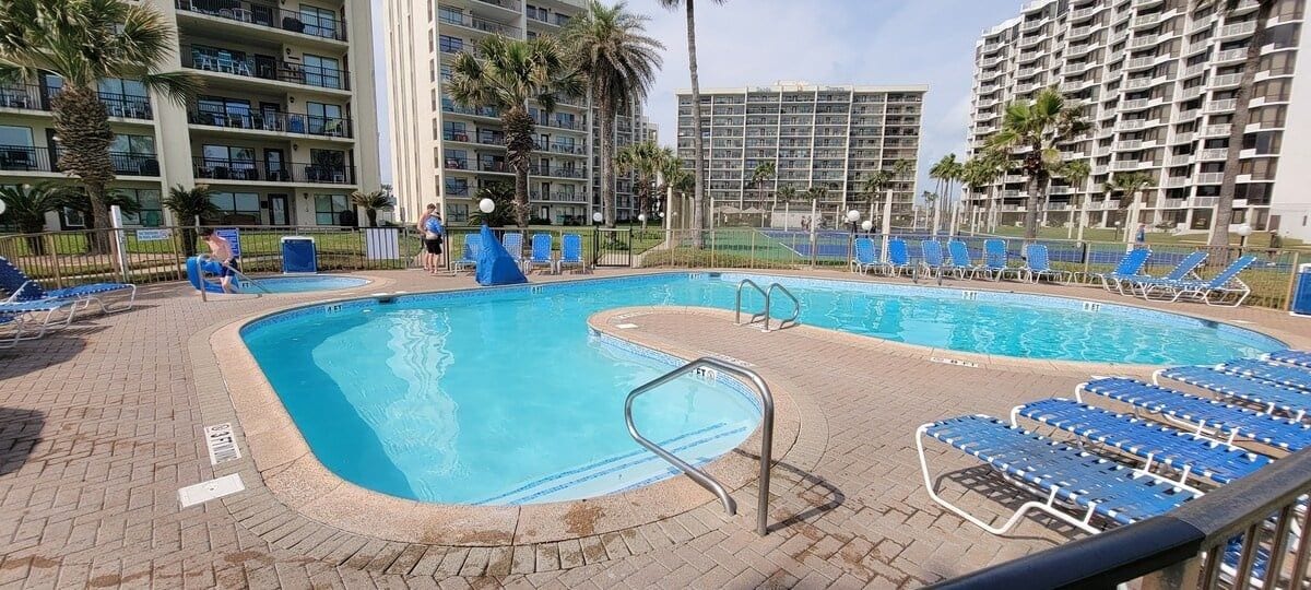 A swimming pool with blue chairs and a lifeguard stand.