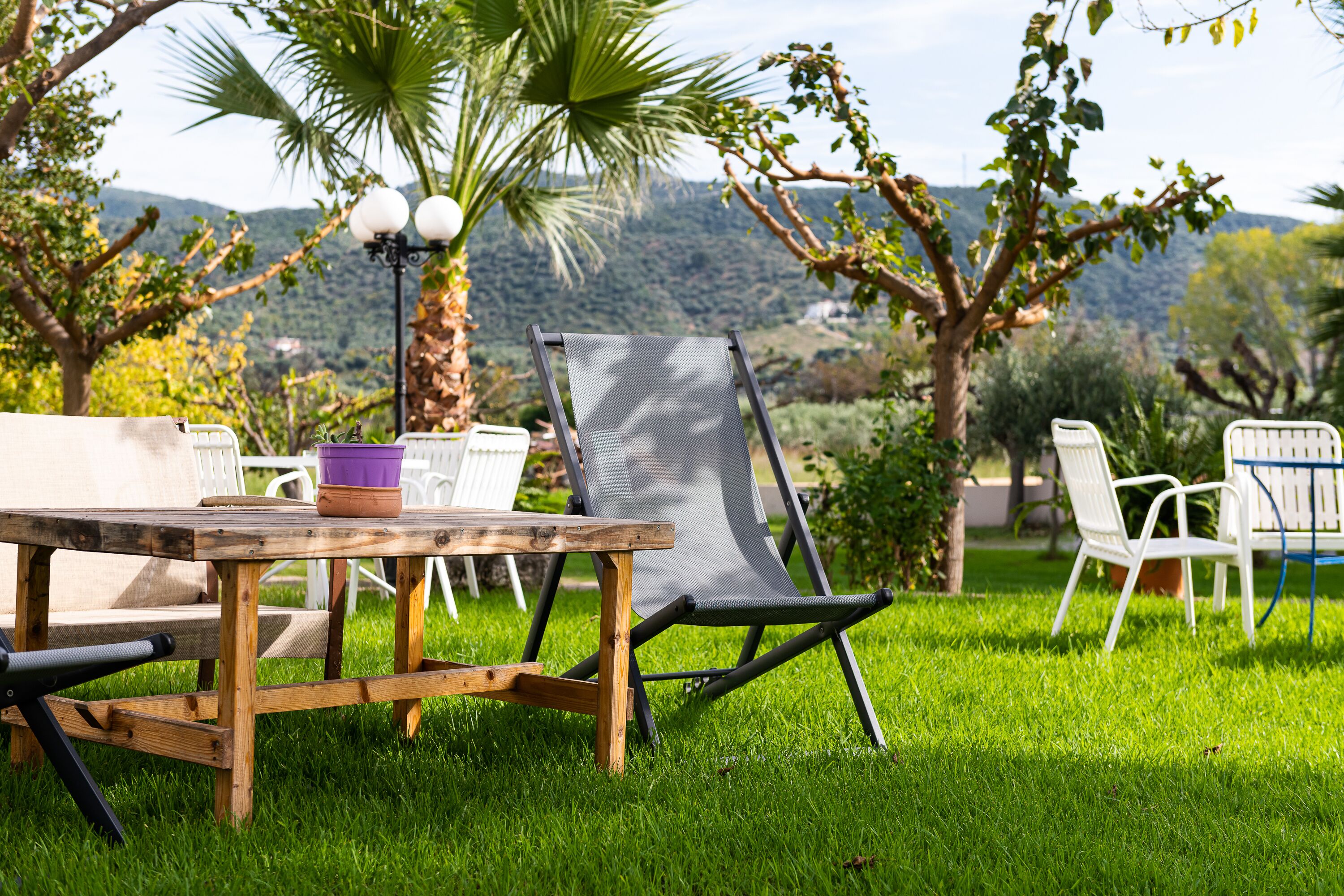 An outdoor seating area with a wooden table, a cushioned chair, and a metal chair.