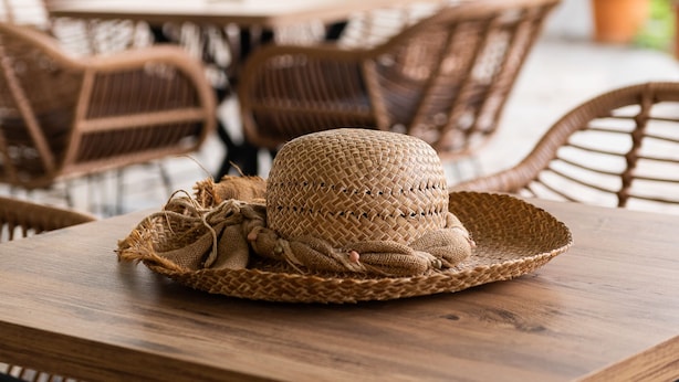 A wooden table with a woven basket and hat, surrounded by wicker chairs in an outdoor setting. - Zoe Seaside (Istiaia-Aidipsos)