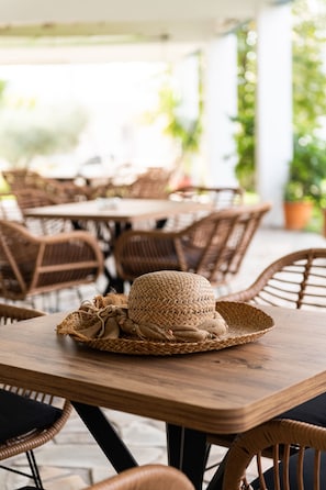 A wooden table with a woven basket and hat, surrounded by wicker chairs in an outdoor setting. - Zoe Seaside (Istiaia-Aidipsos)