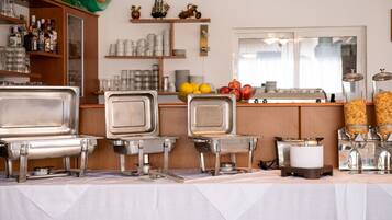 Montaje de bufé con varias estaciones de servicio, una variedad de alimentos y una selección de bebidas.