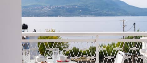 Una terraza con una mesa y sillas, con vistas a un lago y montañas.