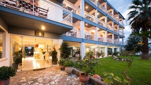 A multi-story hotel with a stone-paved entrance, potted plants, and a well-maintained lawn. - Zoe Seaside (Istiaia-Aidipsos)