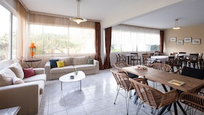 A spacious living area with a sofa, coffee table, dining table, and chairs. - Zoe Seaside (Istiaia-Aidipsos)