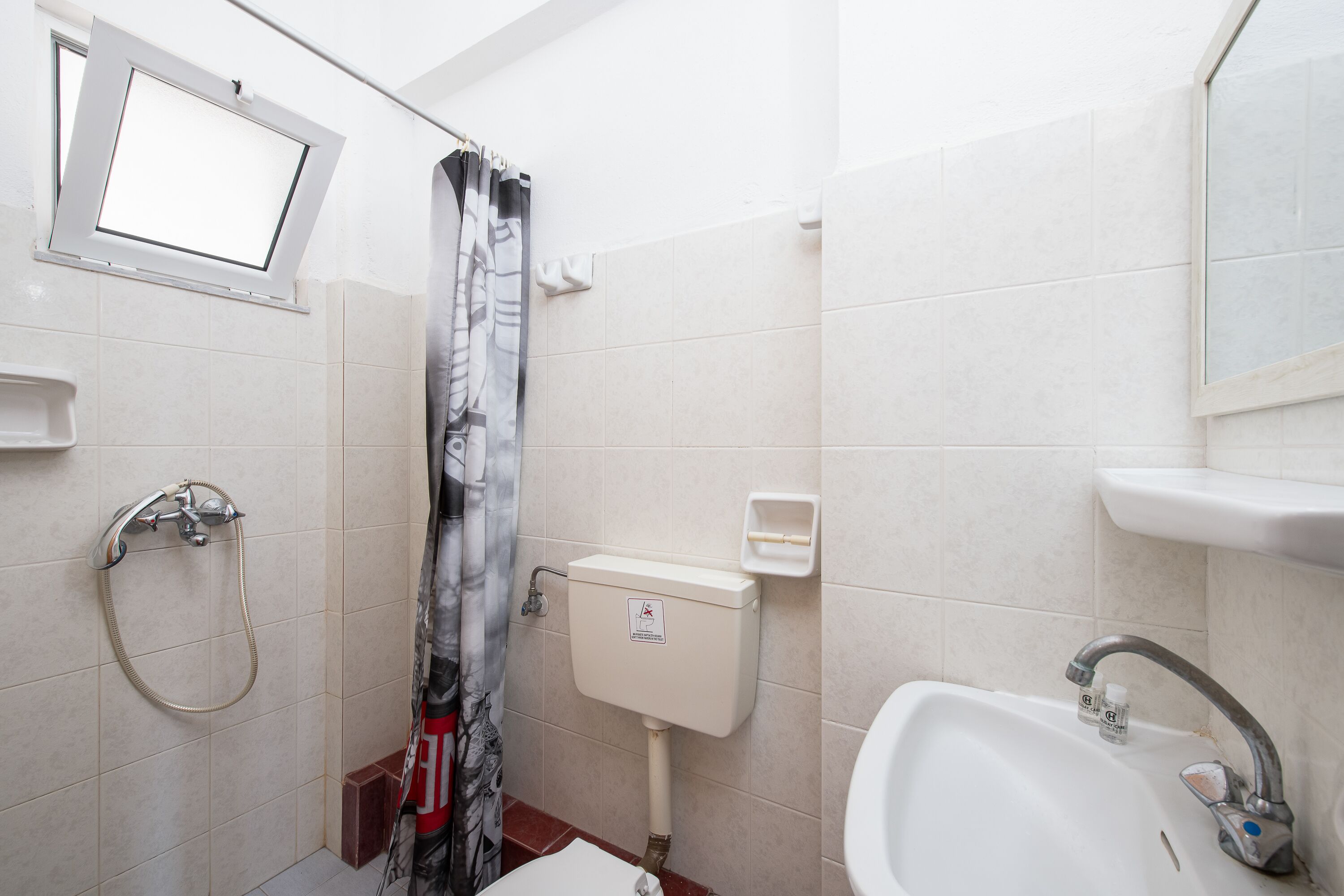 A bathroom with a shower, toilet, sink, and a window.