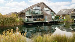 Ein modernes Haus mit einem großen Balkon mit Blick auf ein Gewässer, umgeben von dichter Vegetation.