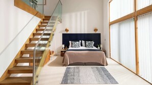 Ein Schlafzimmer mit einem Bett, einer Holztreppe, einem Nachttisch und einem großen Fenster.