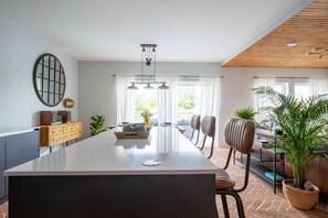 Enjoy meals in the spacious kitchen with a central island, oven, and sink, surrounded by a dining area with a wooden table and chairs.