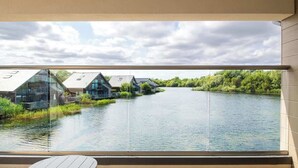 A view from a balcony overlooking a calm river with modern houses on the opposite bank.