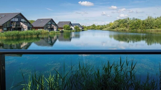 Une vue sur le lac, avec des maisons modernes et un reflet net sur l’eau.