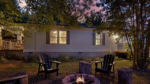Ein Campingplatz mit Feuerstelle, zwei Stühlen und einer Holzterrasse.