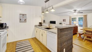 Eine moderne Küche mit weißen Schränken, einer Granitarbeitsplatte, einem eingebauten Geschirrspüler und einem Essbereich mit Holztisch und Stühlen.