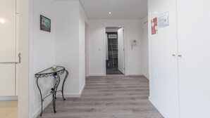 A hallway with a staircase, white walls, and a small table with a rose. - Sea Sound Apartment by Trip2Portugal (Sesimbra)