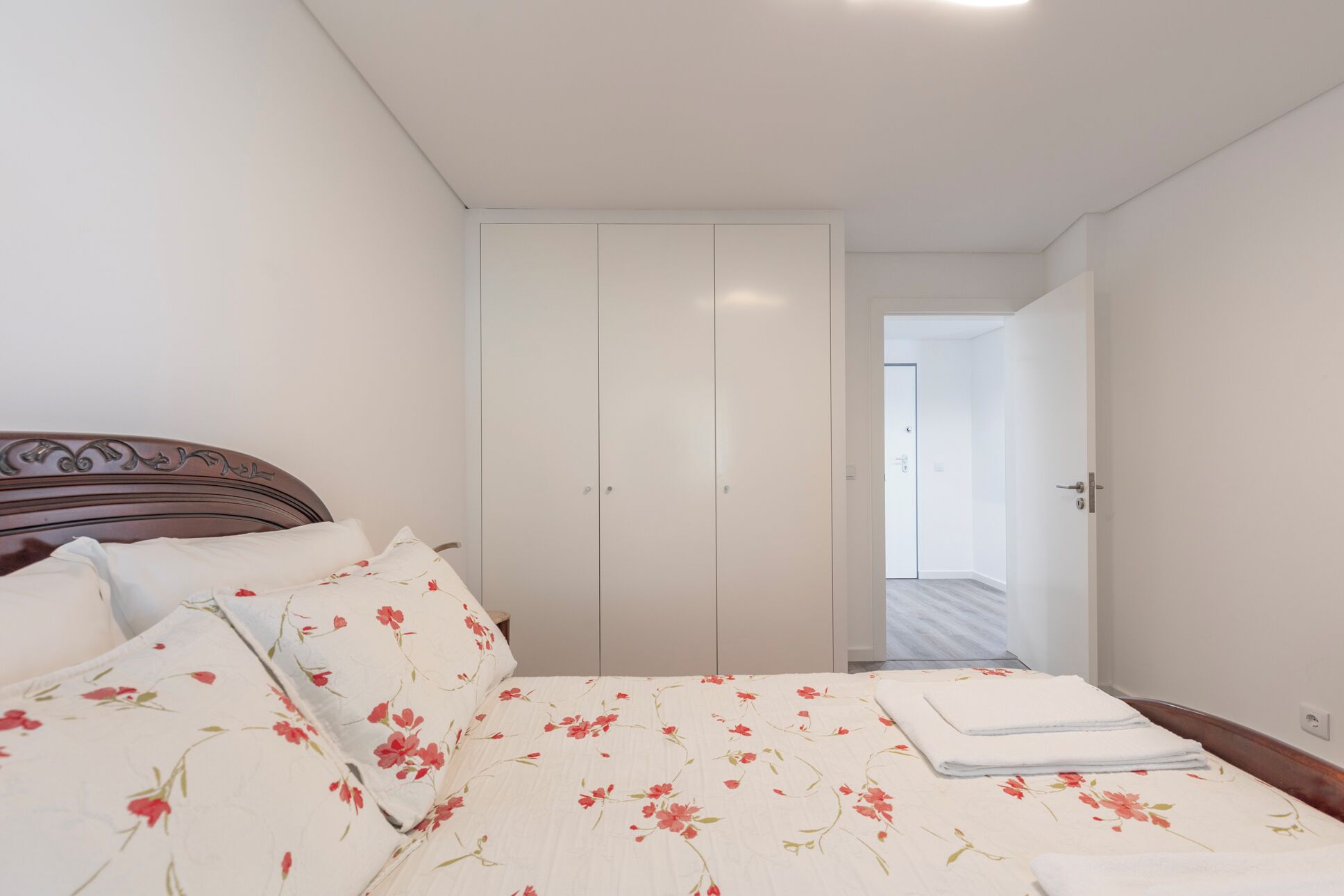 Ein Schlafzimmer mit einem Bett, einem Kleiderschrank und einer Tür zu einem anderen Raum.