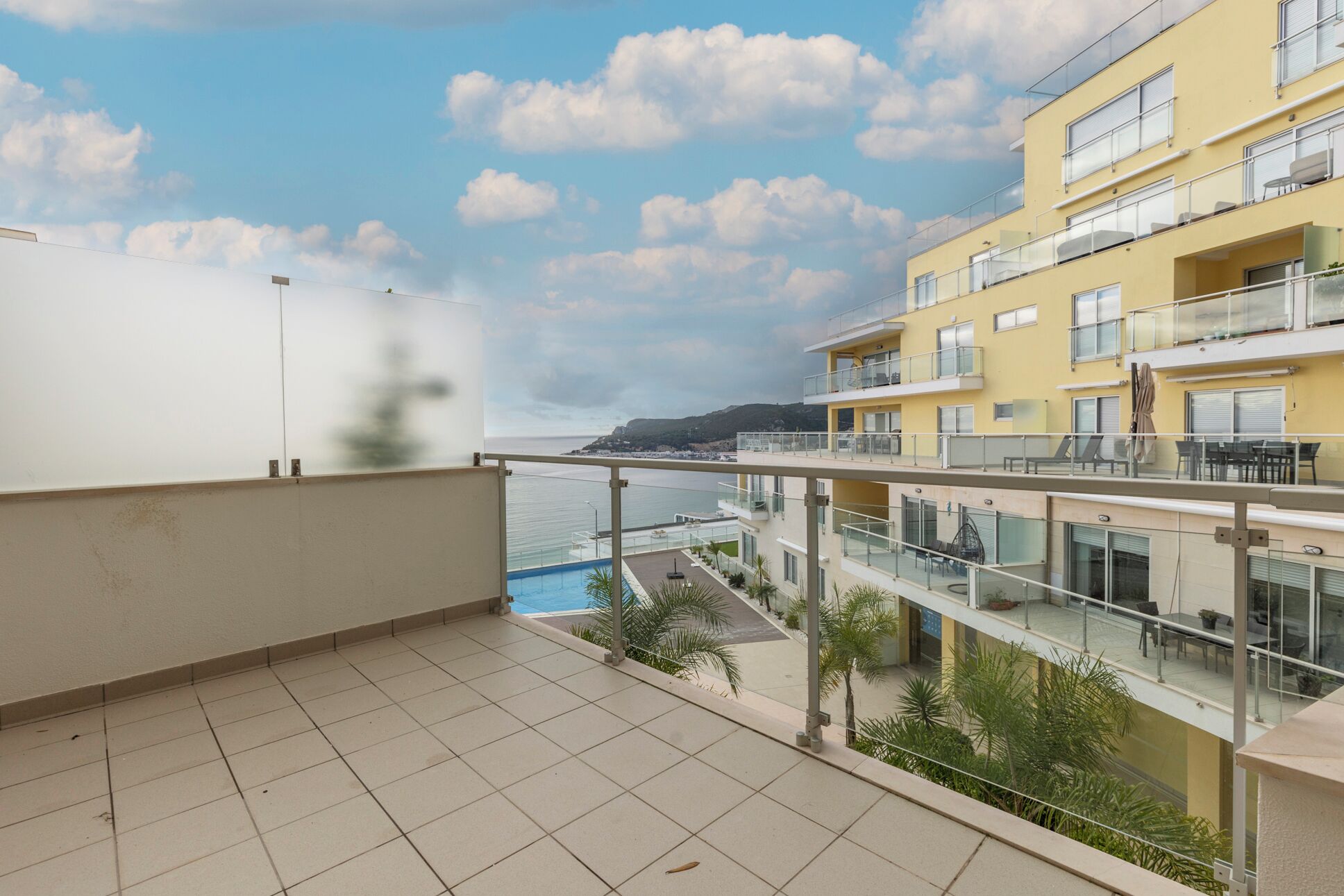En balkon med udsigt til strand og pool.