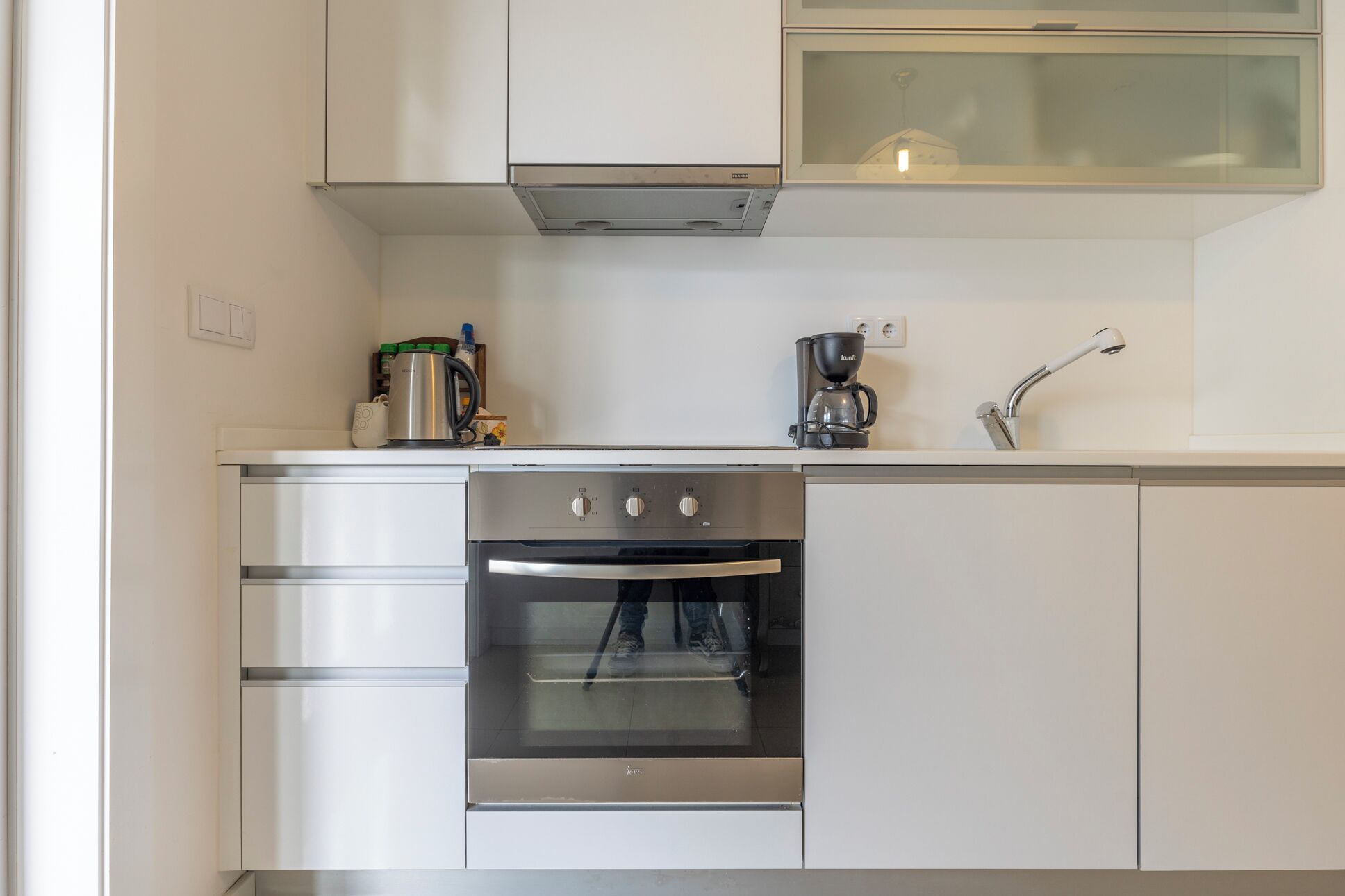 A compact kitchen with stainless steel appliances, including an oven and a coffee maker.