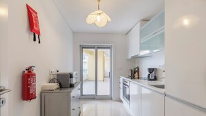 A modern kitchen with white cabinets, a coffee maker, and a fire extinguisher. - Sea Sound Apartment by Trip2Portugal (Sesimbra)
