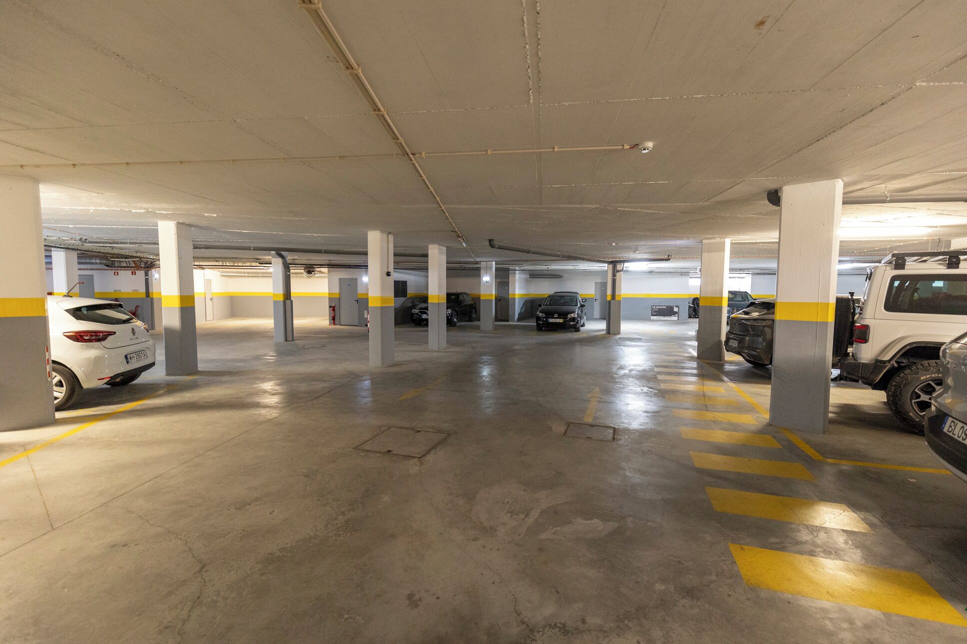 Eine mehrstöckige Parkgarage mit Betonpfeilern und gelben Richtungsmarkierungen.