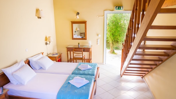 A hotel room with a bed, a desk, and a staircase. - Olive Trees Garden Lixouri (Kefalonia)