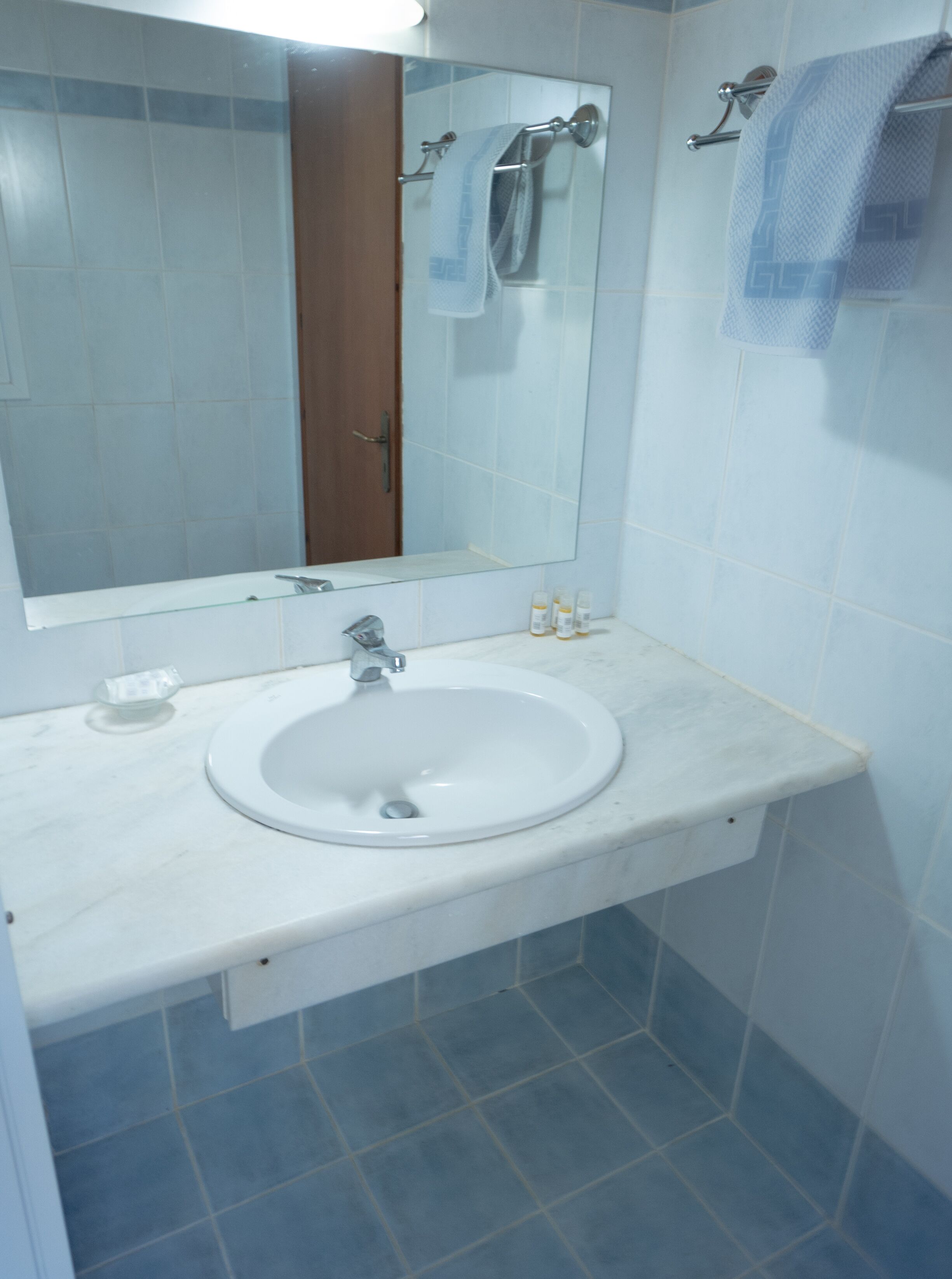 A bathroom with a white sink, a mirror, and a towel rack.