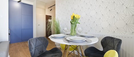 A dining area with a round table set for four, surrounded by modern chairs.