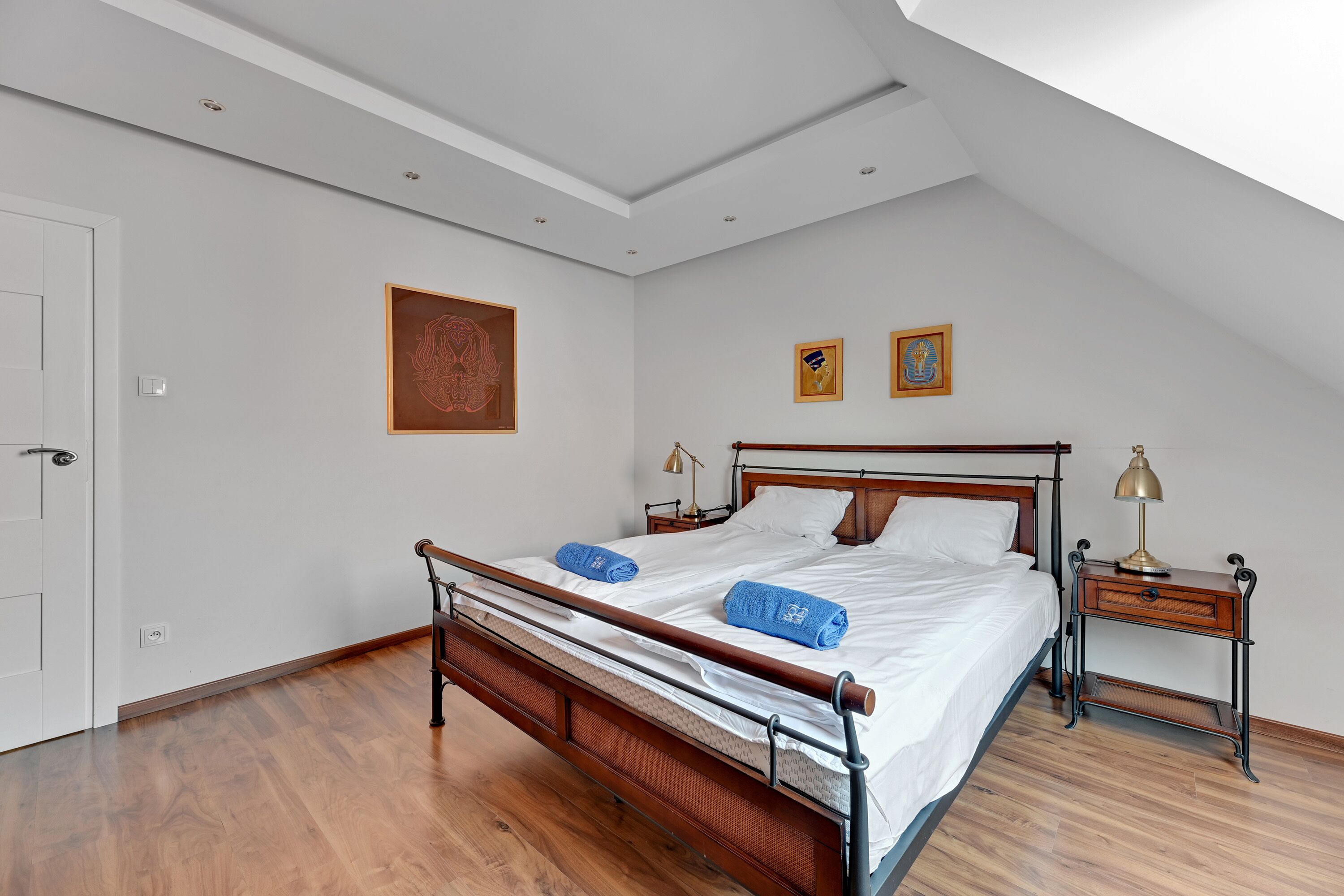 A bedroom with a wooden bed, two bedside tables, and a ceiling light.