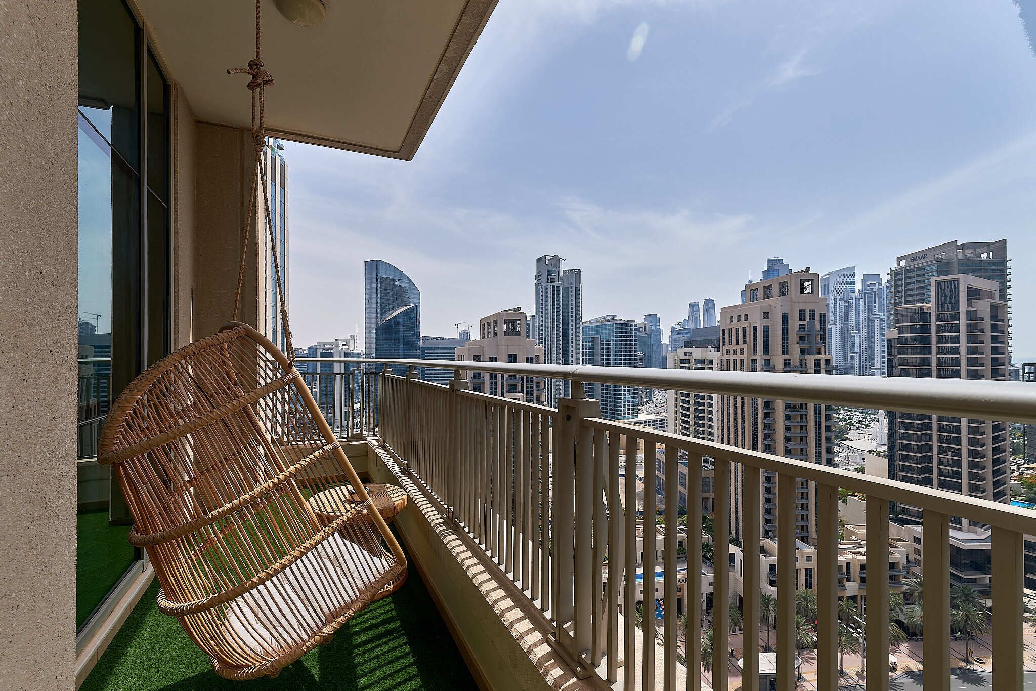 Ein Balkon mit Korbstuhl, Geländer und Blick auf die Stadt.