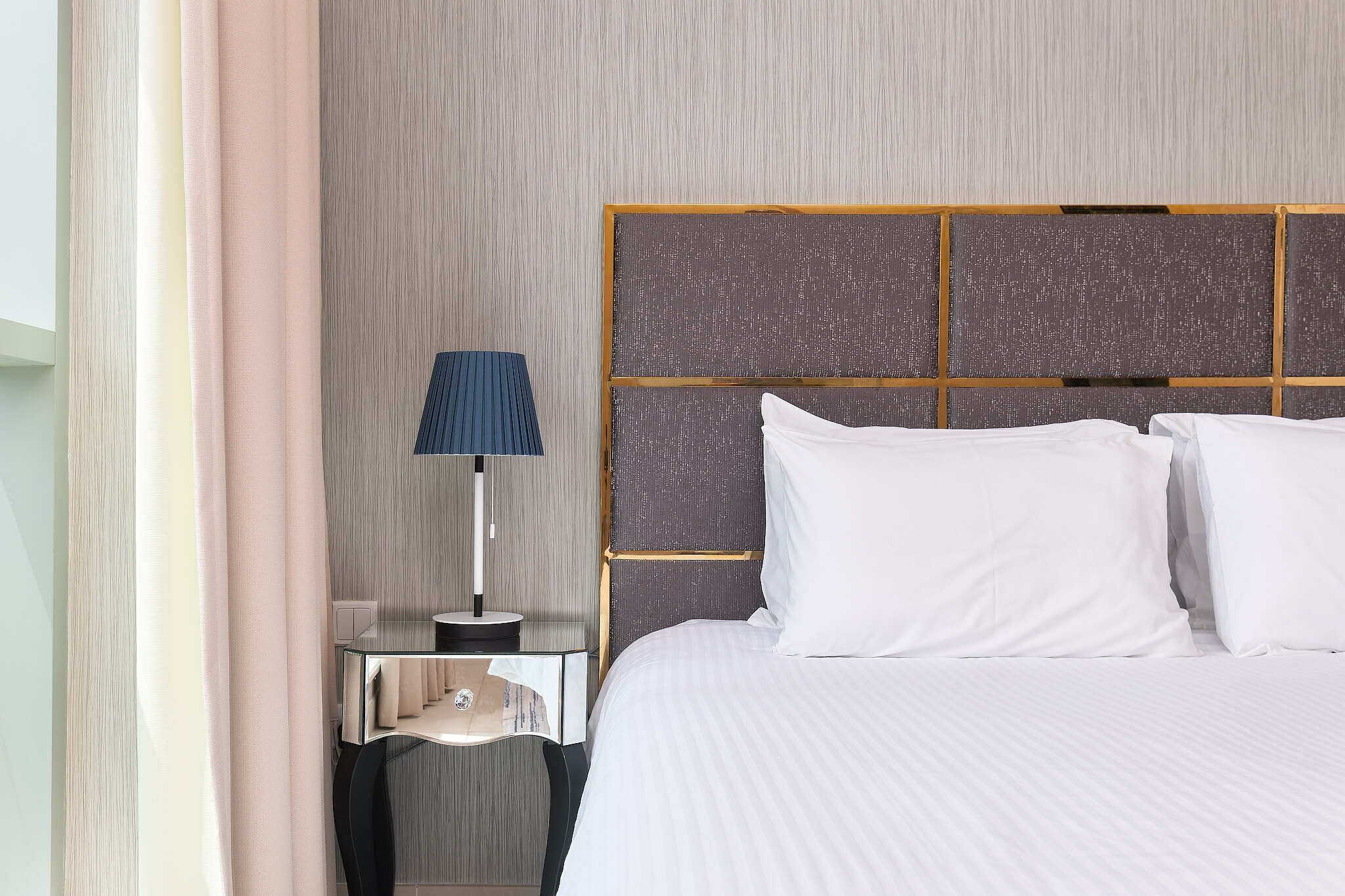 Ein Hotelzimmer mit einem großen Bett, einem Nachttisch mit Lampe und einer strukturierten Wand.