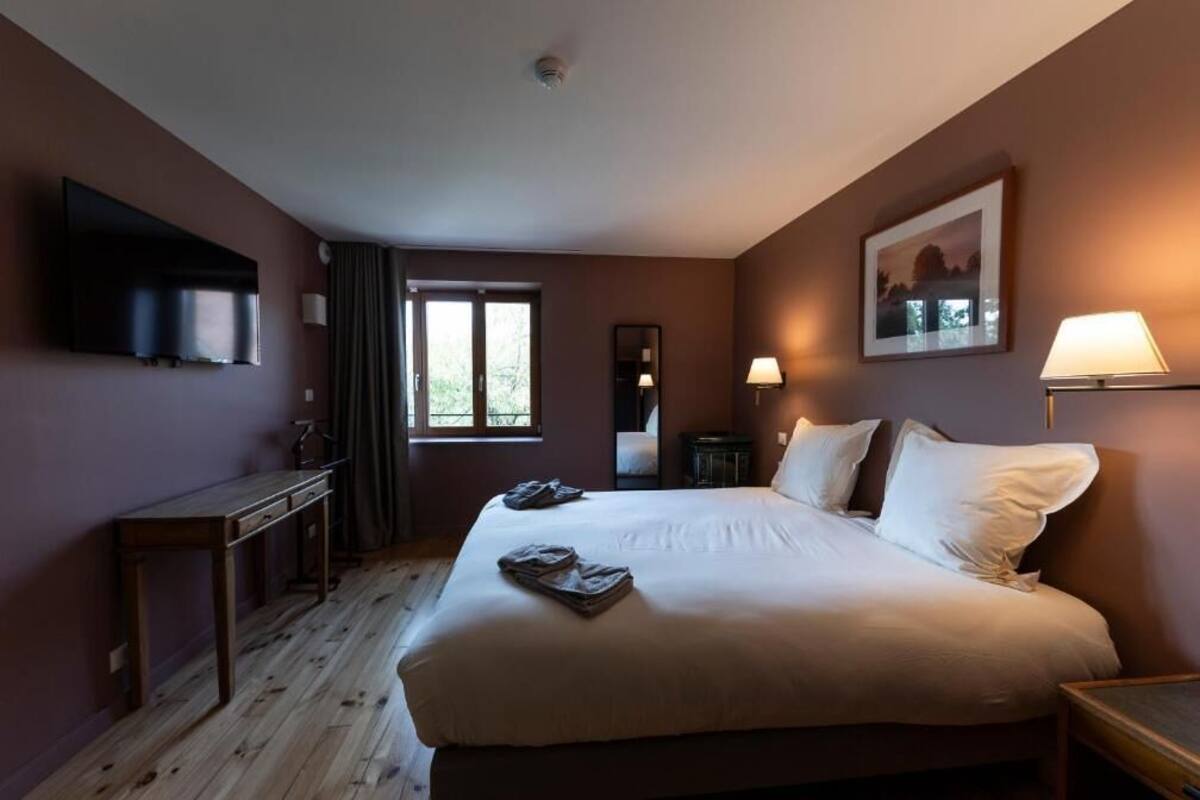 Hotellihuone, jossa on sänky, työpöytä, televisio, ikkuna ja lamppu.