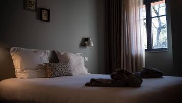 A bedroom with a bed, pillows, a lamp, and a window with curtains.