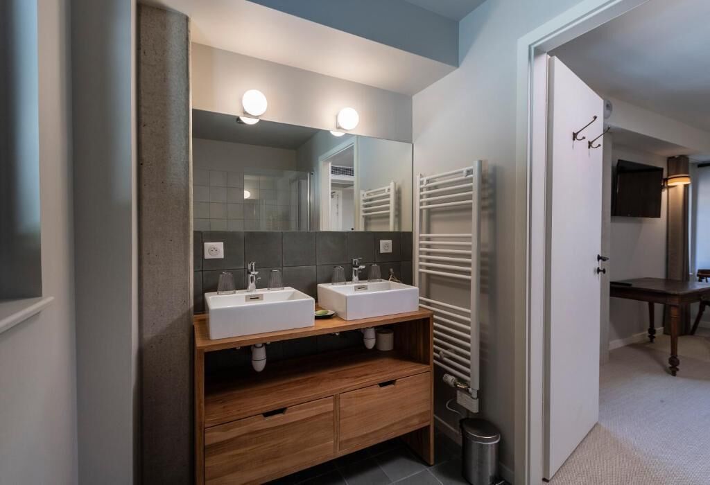 A bathroom with two sinks, a mirror, and a towel rack.