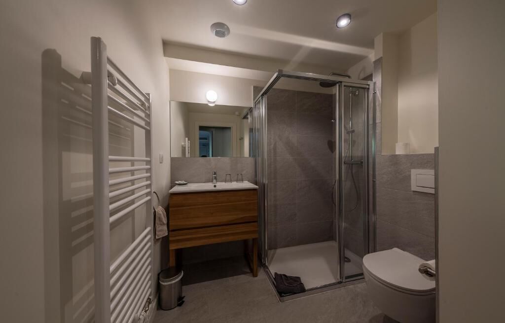 A modern bathroom with a glass shower enclosure, a wooden vanity, and a white toilet.