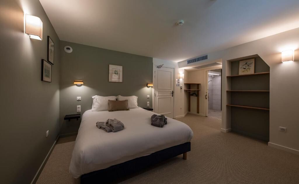 A bedroom with a bed, bedside tables, a wardrobe, and a door leading to another room.