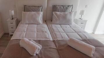 A double bed with two pillows, a bedside table with a lamp, and a folded towel on the bed.