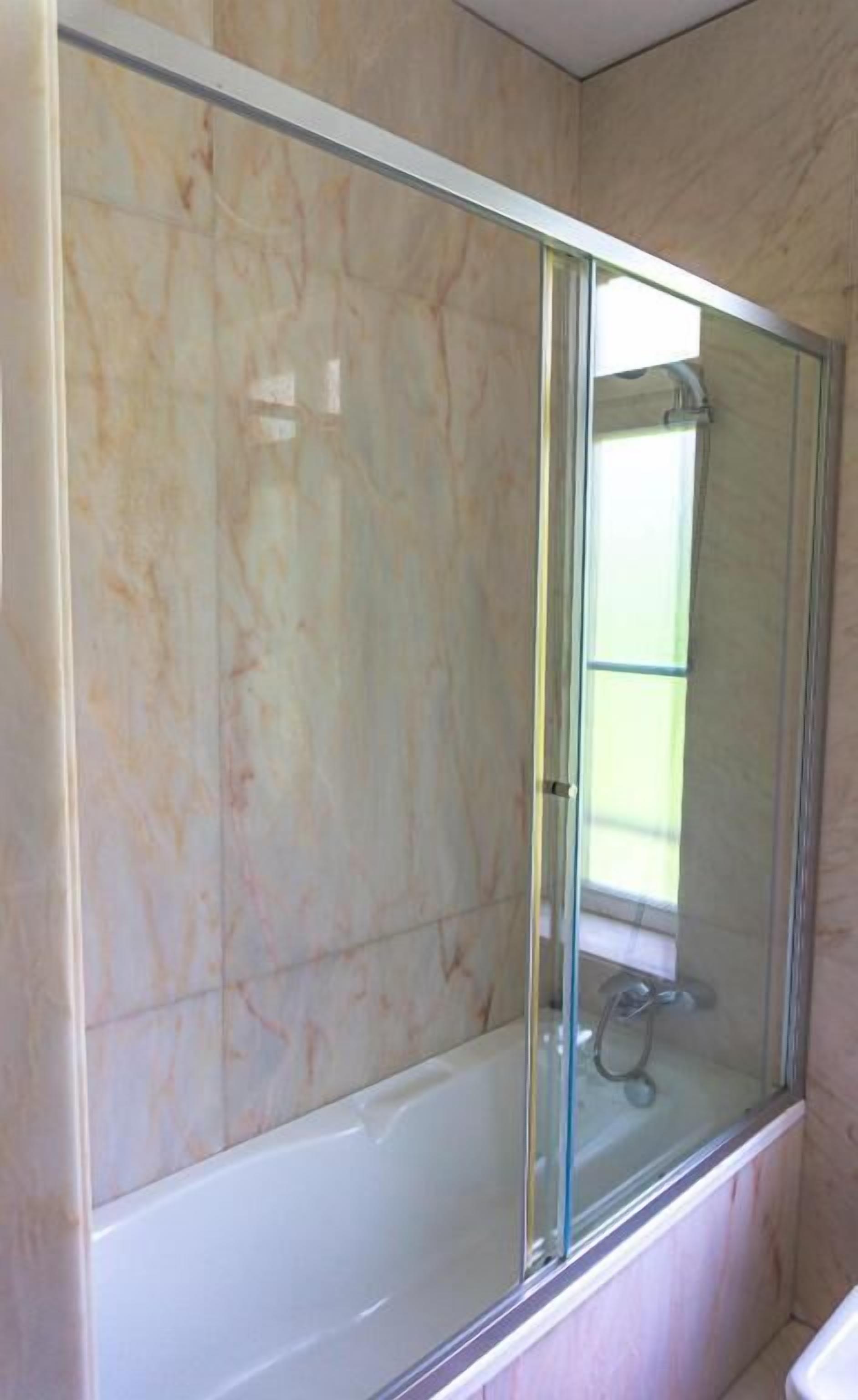 A bathroom with a glass-enclosed shower and a white bathtub.