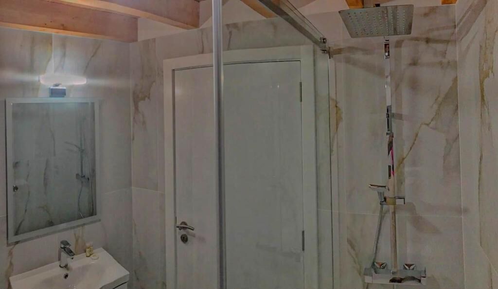 Un baño con cabina de ducha de vidrio, lavamanos y espejo.