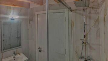 Un baño con cabina de ducha de vidrio, lavamanos y espejo.