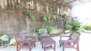 Une terrasse avec des meubles en bois et des plantes en pot, adossée à un mur en béton.