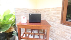 Une petite table en bois, sur laquelle se trouvent un ordinateur portable et une pancarte blanche.