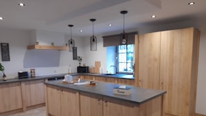 A modern kitchen with wooden cabinets, a central island, and pendant lighting.