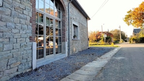 A stone building with large windows and a gravel pathway.